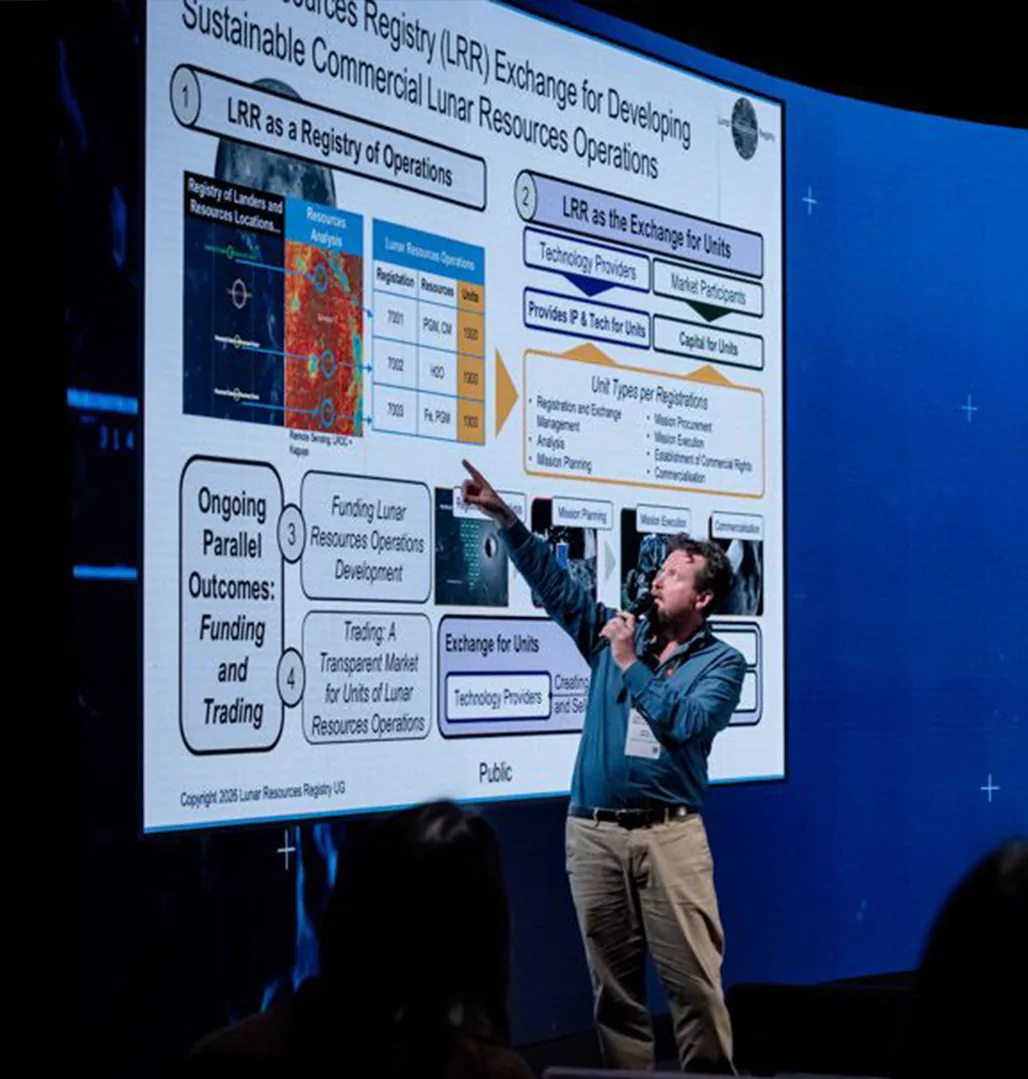 Simon Drake on stage explaining a presentation slide about the Lunar Resources Registry